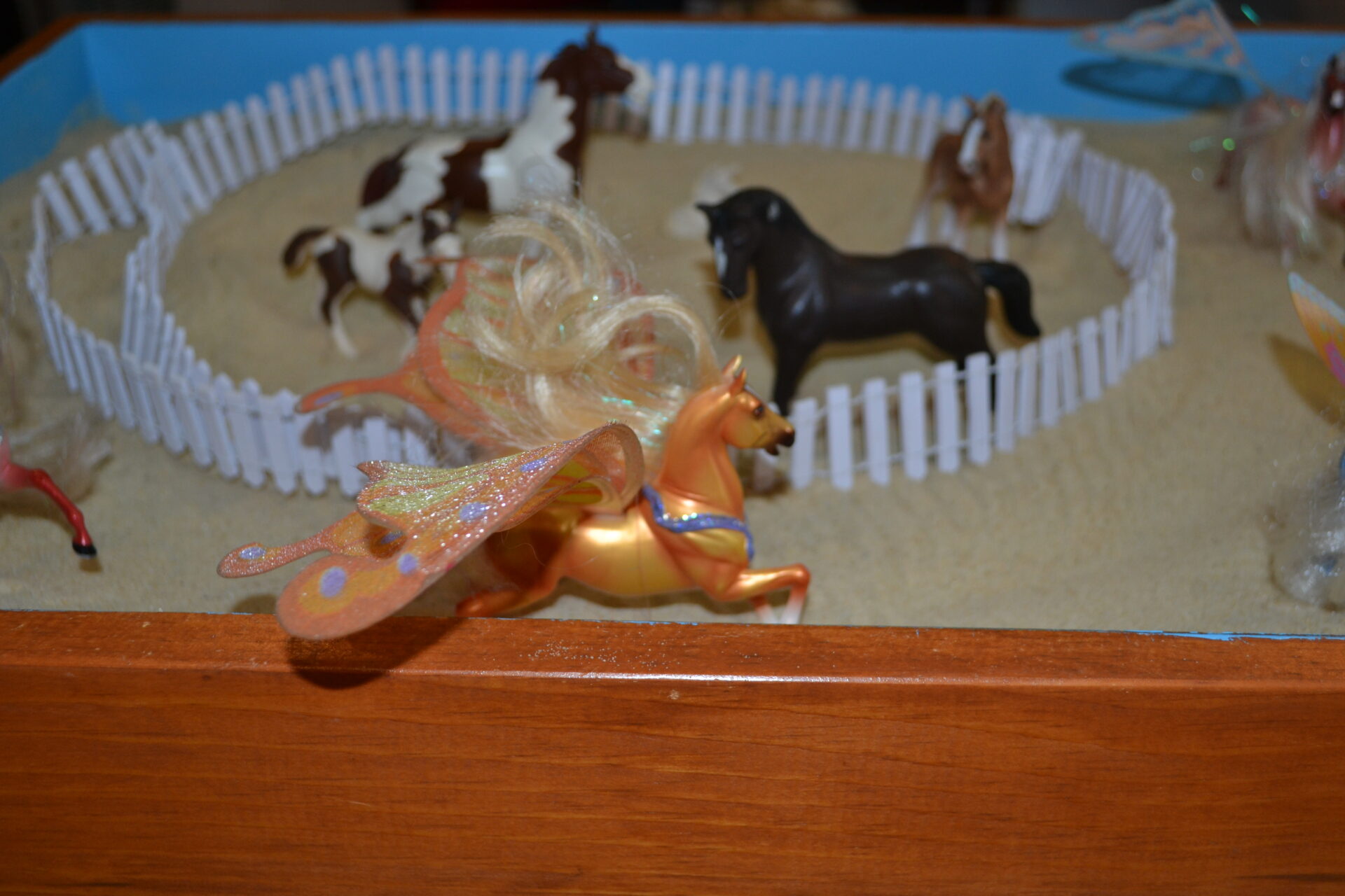 A table with some toy horses and a fence