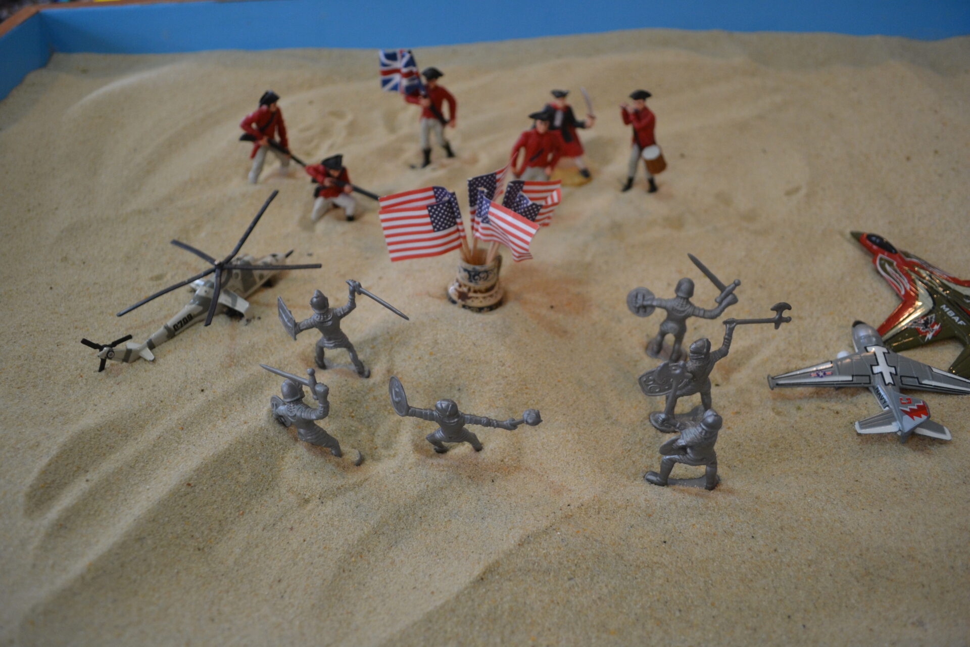 A group of toy soldiers in the sand.